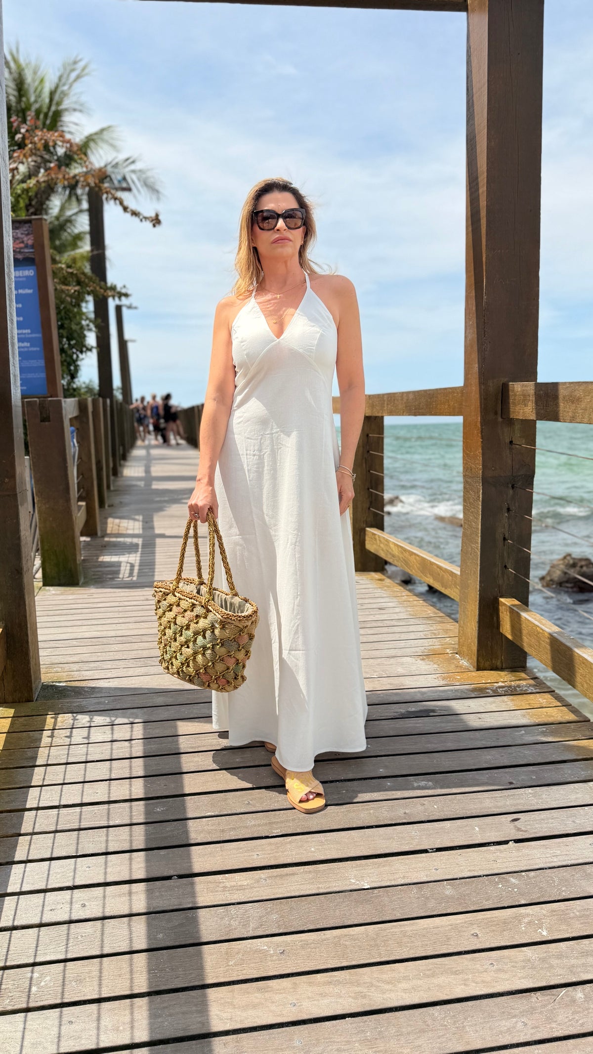 Um vestido longo, fluido e elegante com decote em V e alças finas que se cruzam nas costas com regulagem