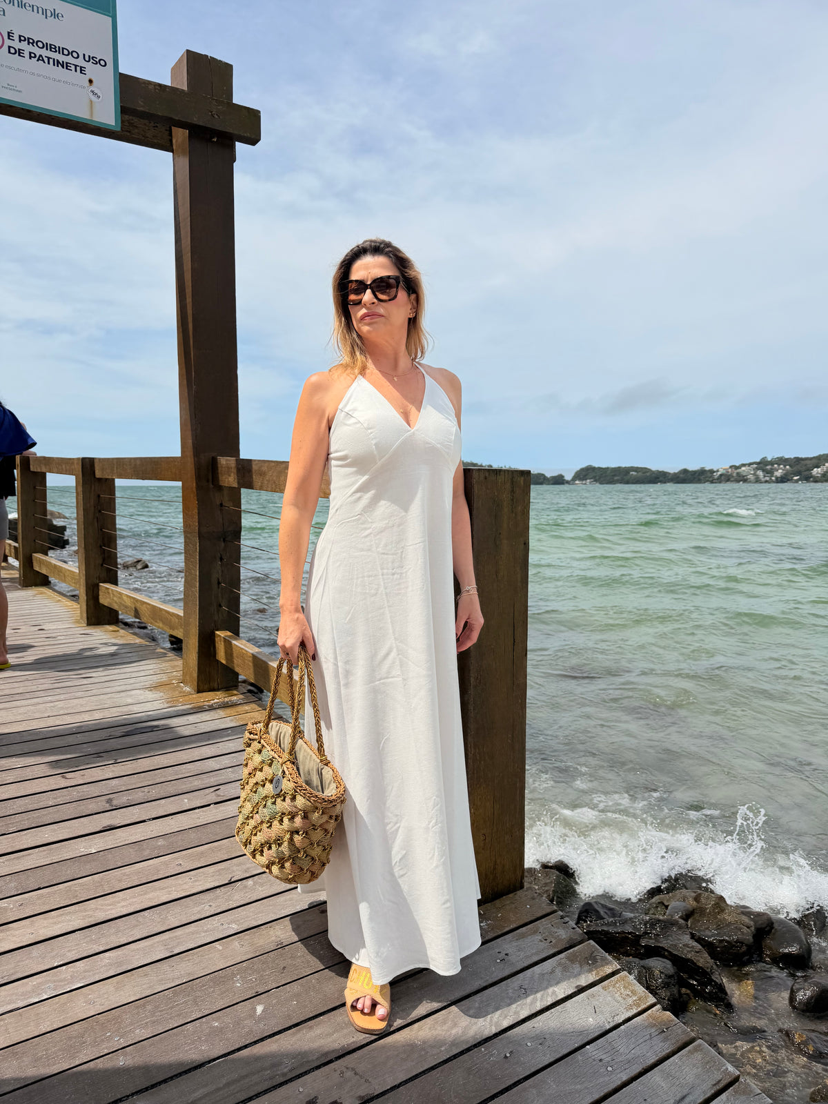 Um vestido longo, fluido e elegante com decote em V e alças finas que se cruzam nas costas com regulagem