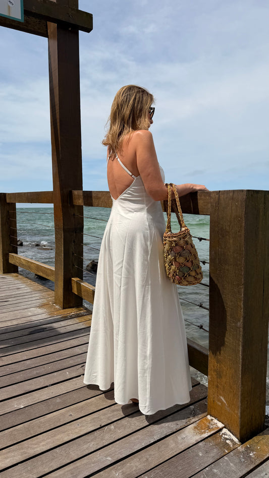 Um vestido longo, fluido e elegante com decote em V e alças finas que se cruzam nas costas com regulagem