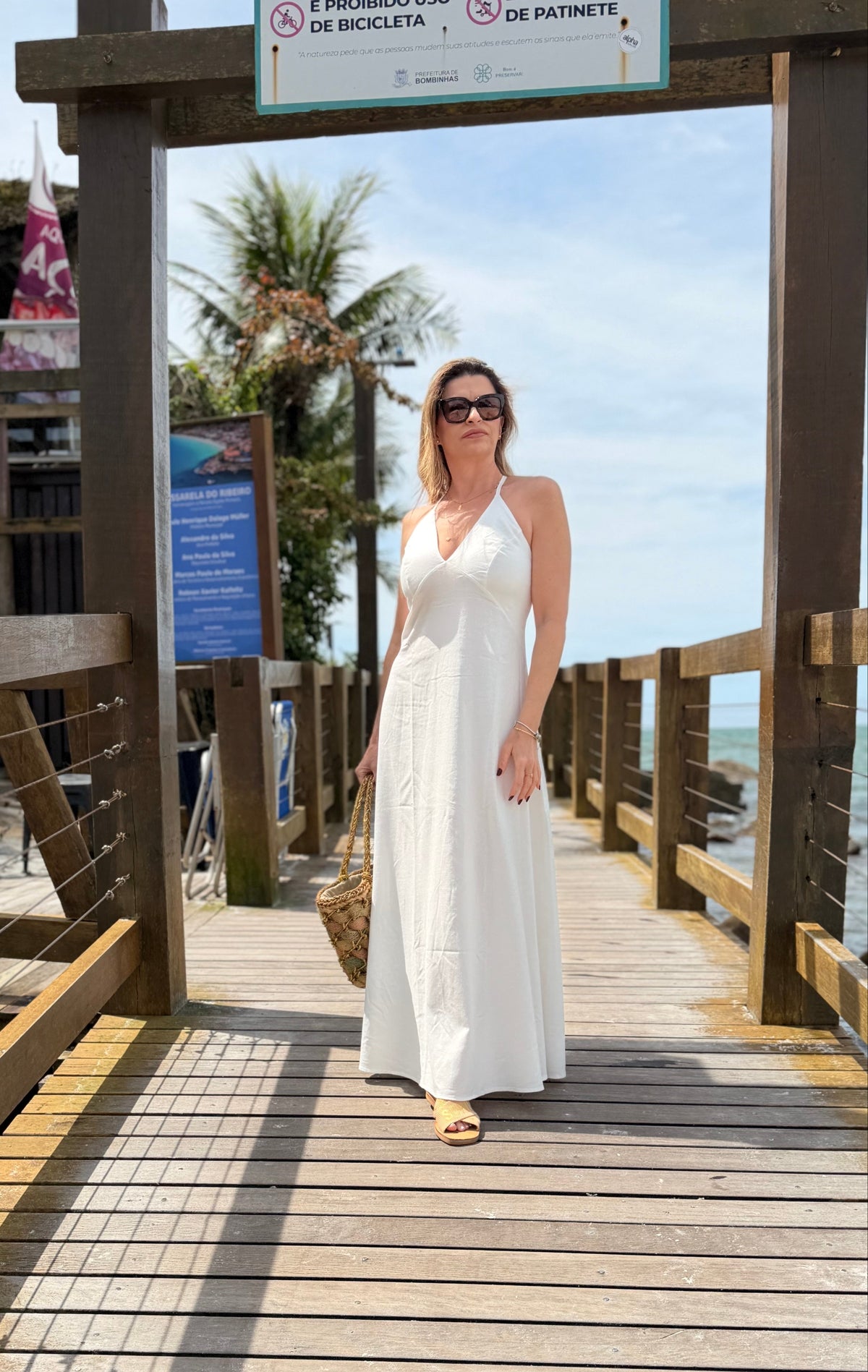 Um vestido longo, fluido e elegante com decote em V e alças finas que se cruzam nas costas com regulagem