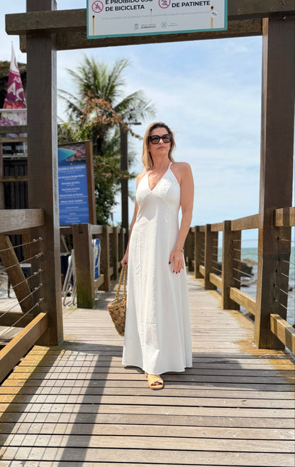 Um vestido longo, fluido e elegante com decote em V e alças finas que se cruzam nas costas com regulagem